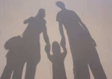 Family holding hands in a shadow