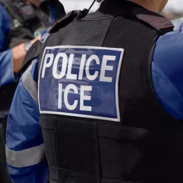 Closeup photo of ICE officer wearing a black vest that says Police ICE