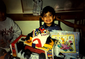 José as young child celebrating a birthday with cake and presents
