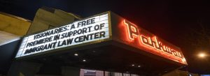 Outside the Parkway Theater looking at the neon sign saying "Visionaries: A Free Premiere in support of Immigrant Law Center"