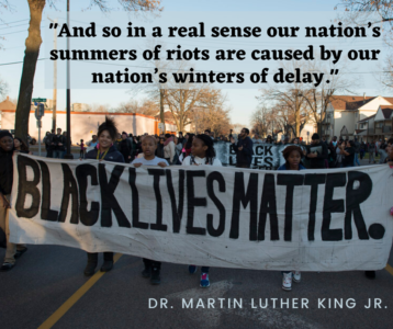 "and so in a real sense our nation's summers of riots are caused by our nation's winters of delay" - Dr. Martin Luther King Jr. marchers march with large banner stating black lives matter.
